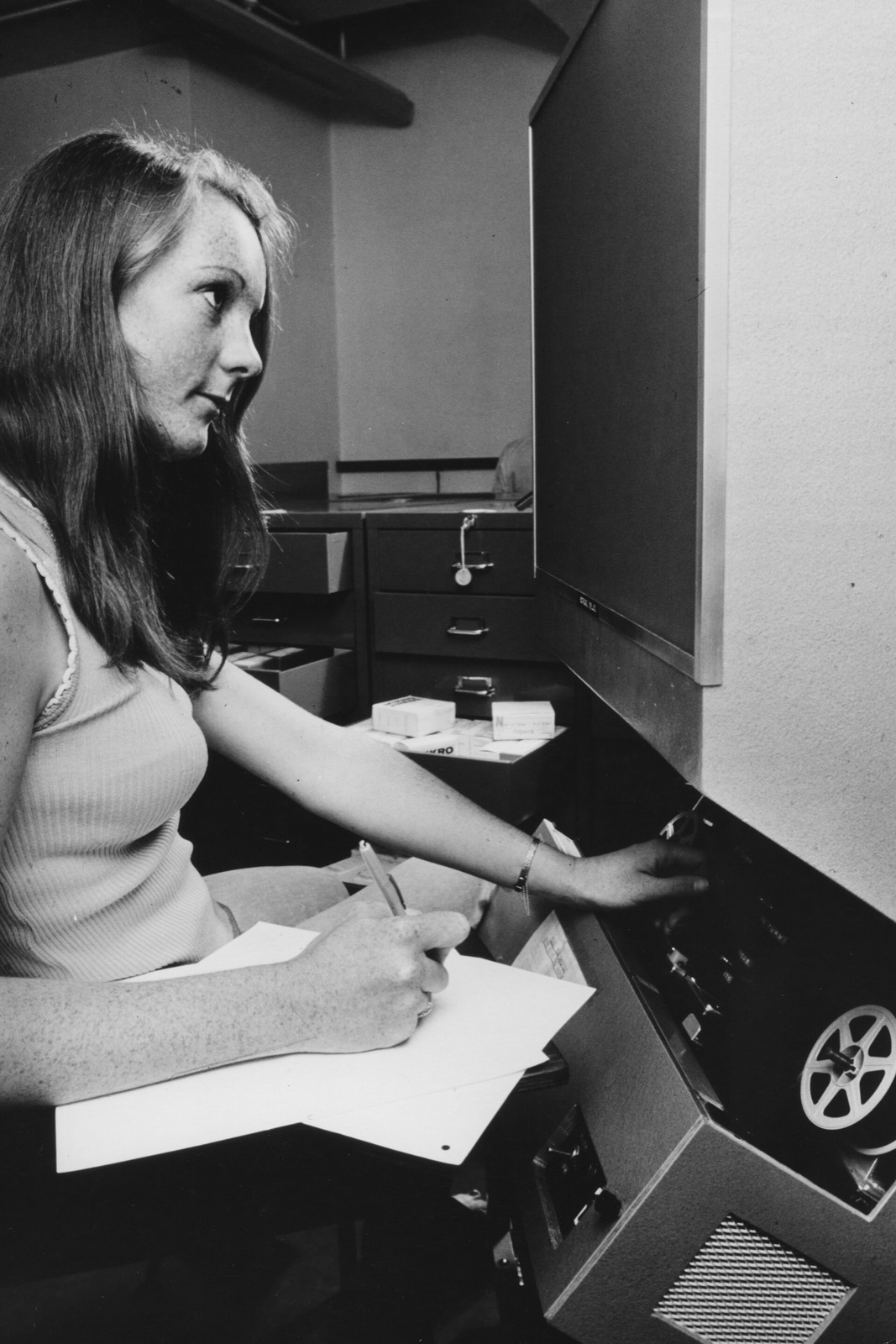 A student takes notes at a microfilm reader